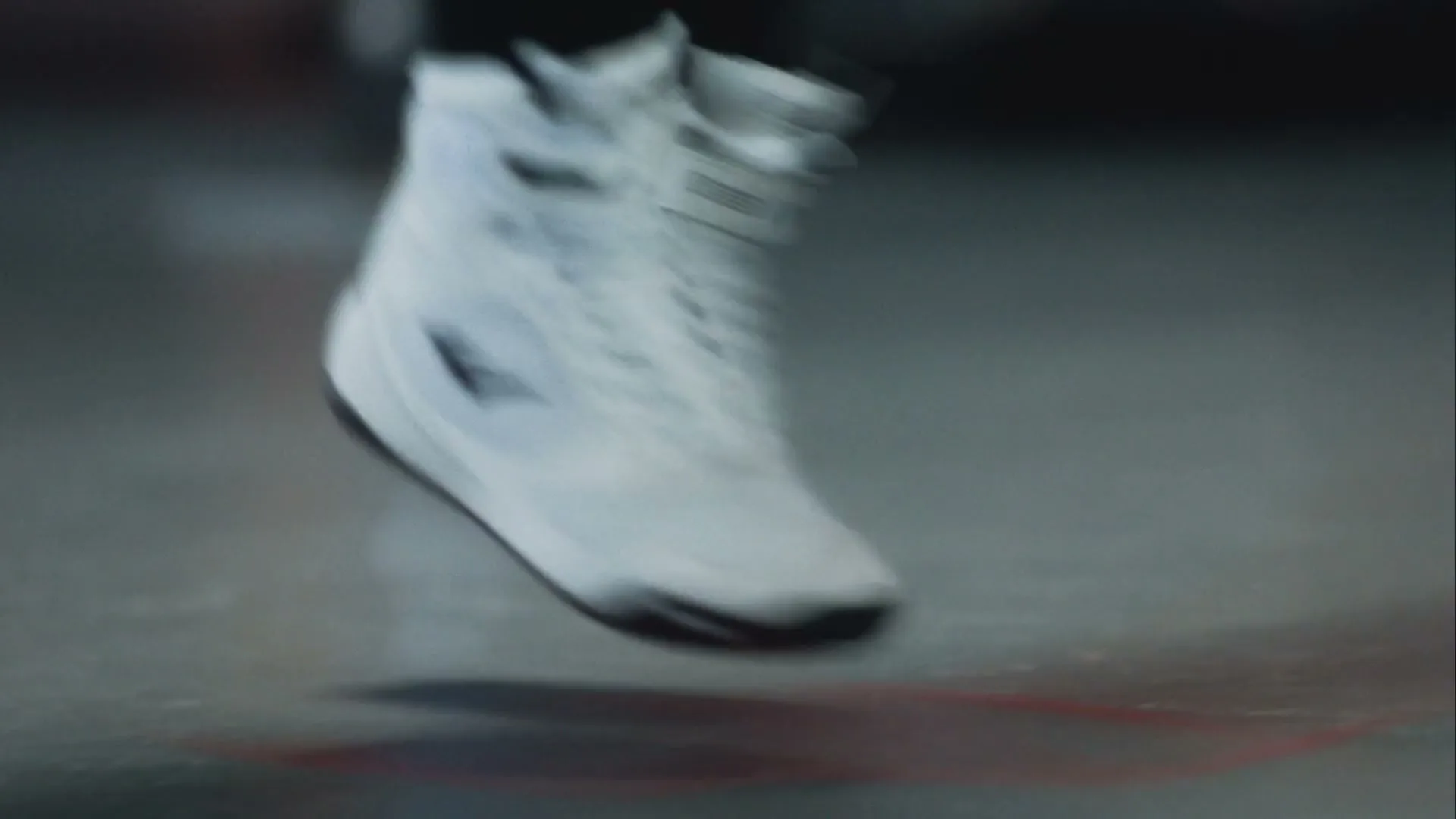 A person wearing white Everlast boxing boots and black leggings jumps rope on a grey floor in an interior setting.