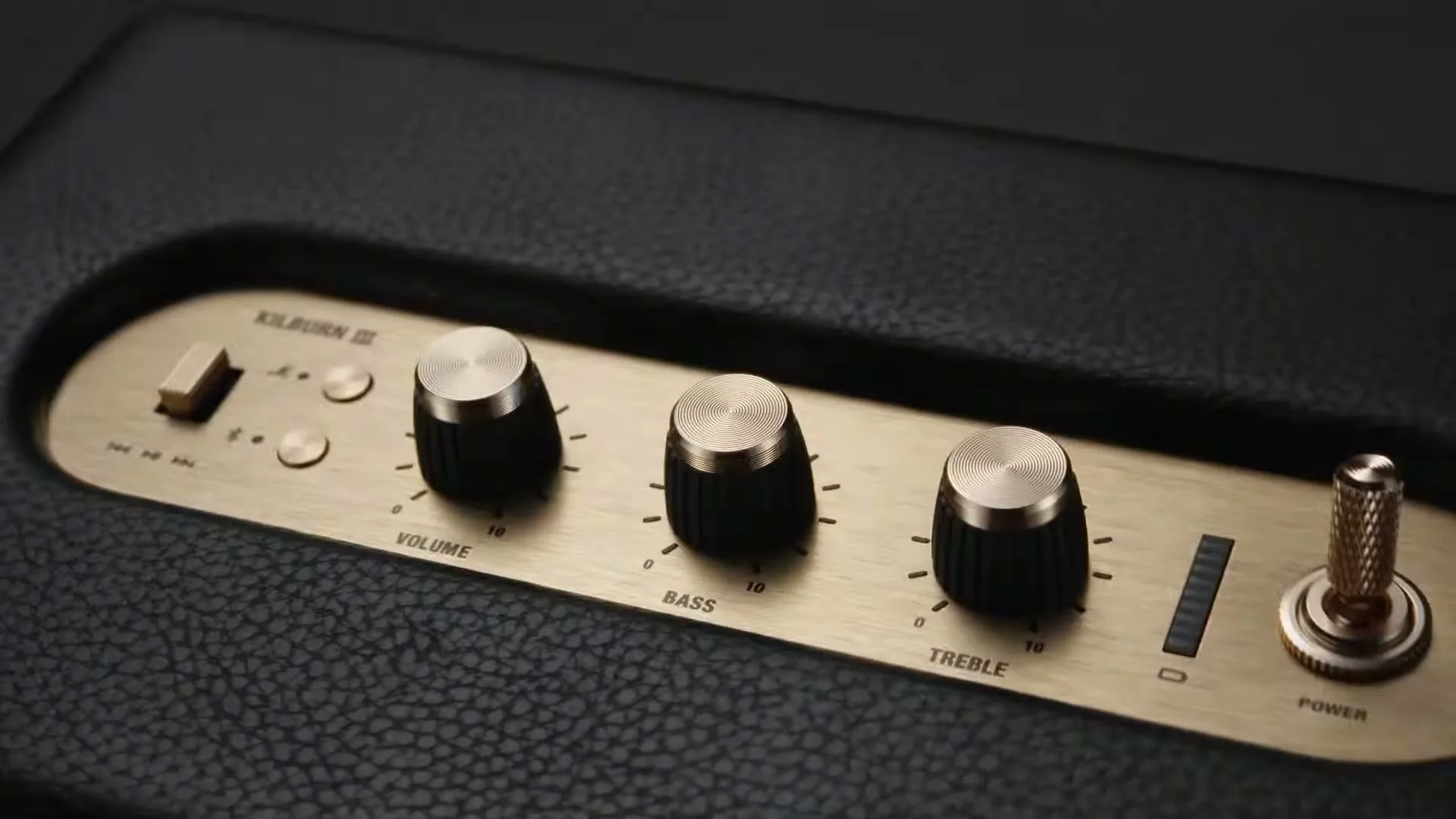 A close-up shot of the control panel of a black Marshall speaker with gold-colored knobs and switches.