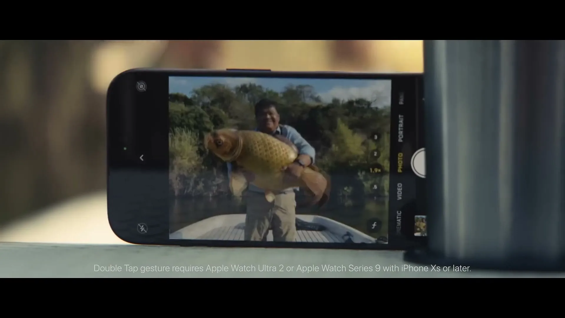 A close-up shot of an iPhone screen displaying a man holding a large fish on a boat, with a legal disclaimer at the bottom.