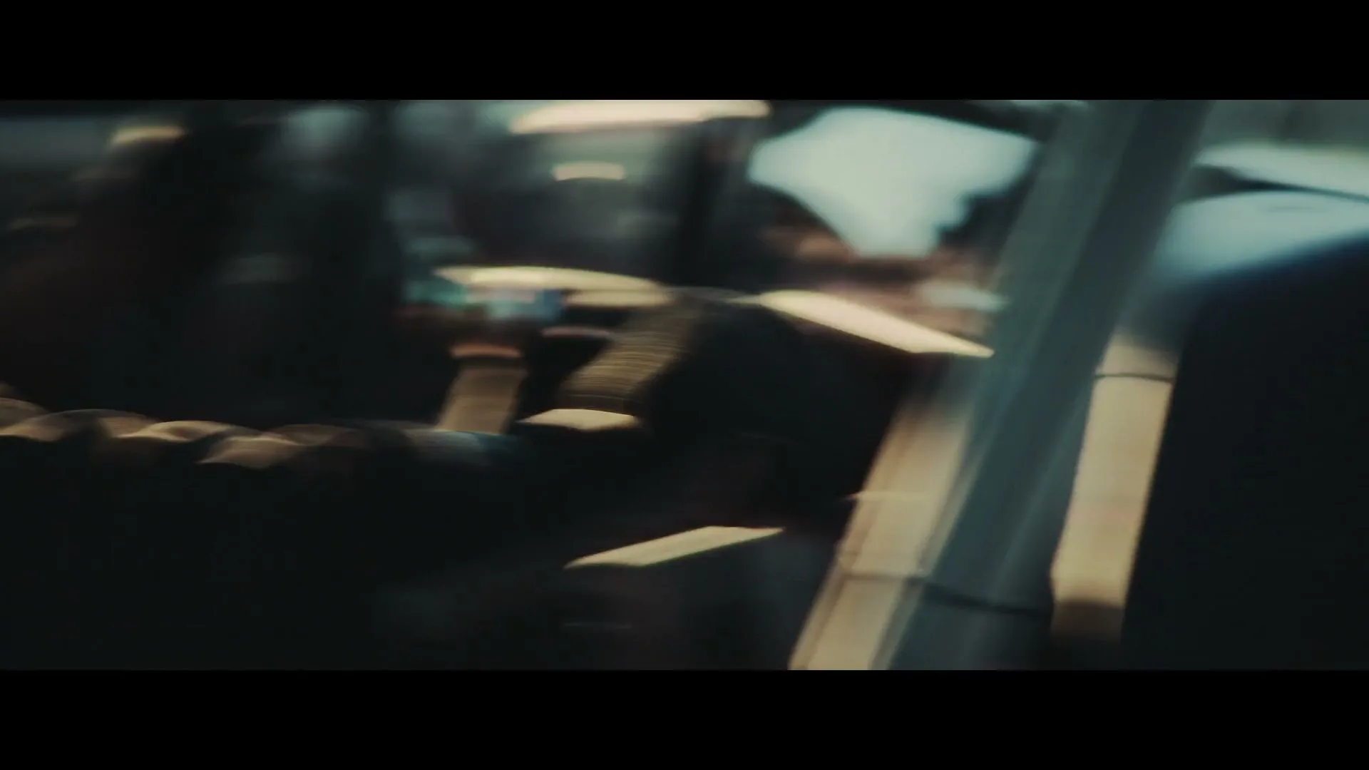 A driver's gloved hand shifts gears in a race car, with sunlight streaming through the window, creating a dramatic, high-contrast scene.