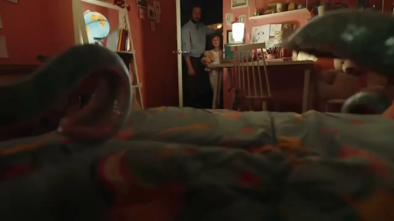A father and his young daughter, holding a teddy bear, stand in a doorway looking into a child's bedroom, with a large green tentacle visible in the foreground.