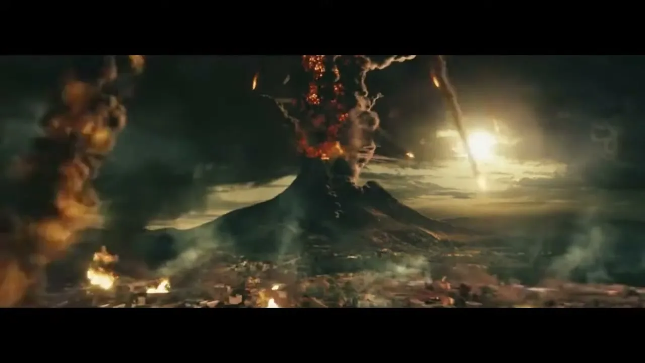 A wide shot shows a volcano erupting, spewing lava and smoke into the dark sky, with a city below engulfed in flames and falling debris.