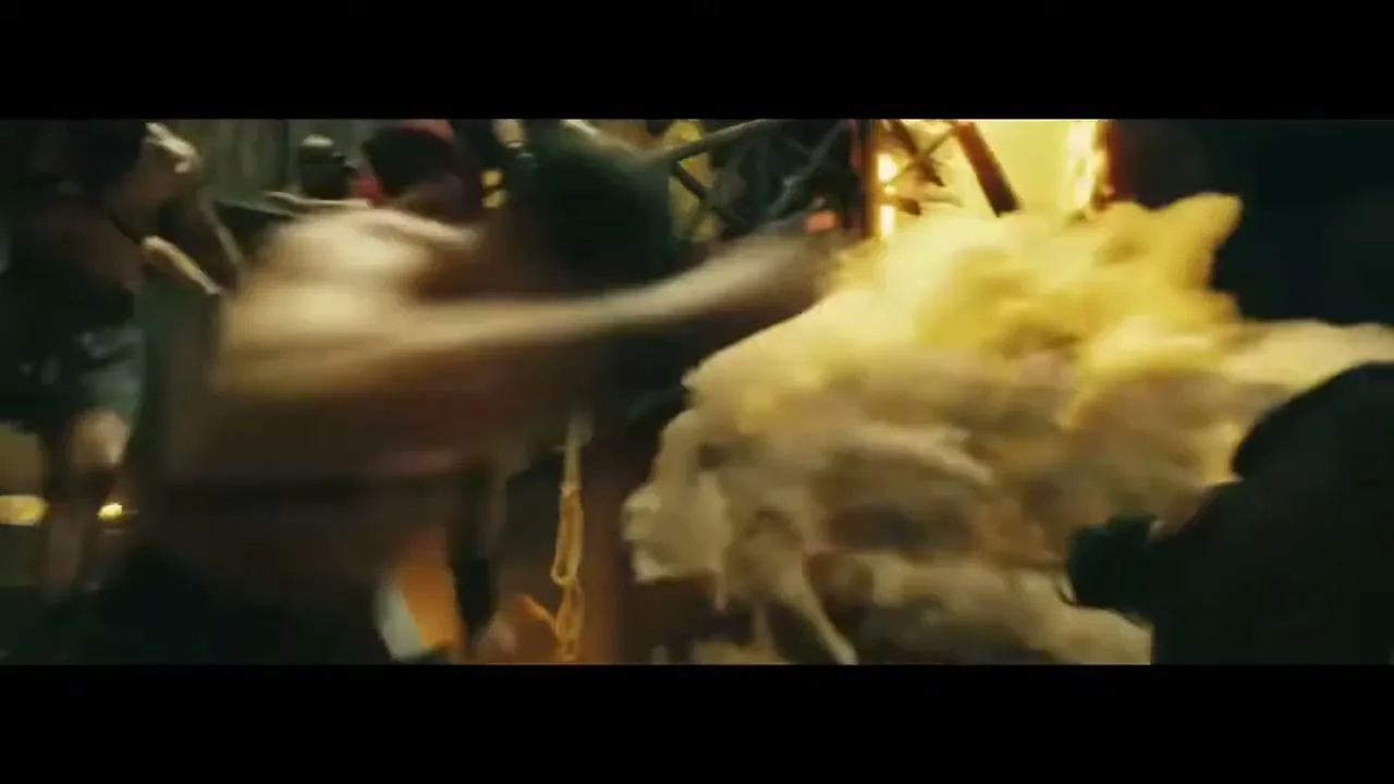 A man in ancient Roman attire fights a lion in a chaotic arena, as fire and smoke fill the air during a volcanic eruption.