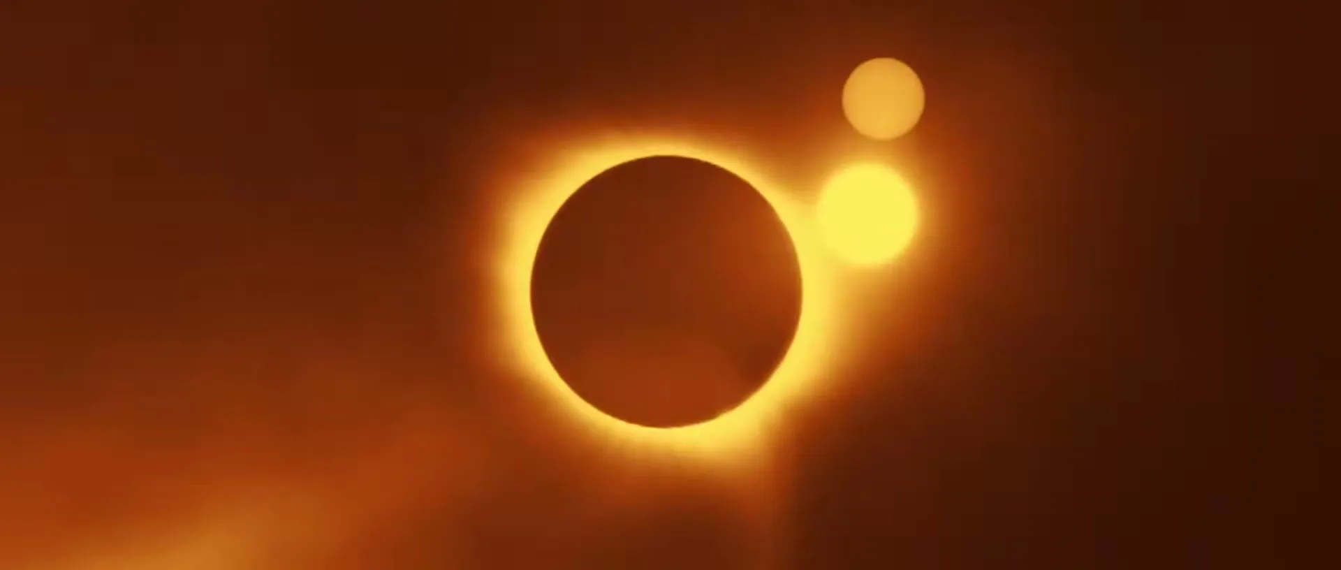 A dark circular shape with a bright orange glow around it, resembling a solar eclipse, is centered against an orange background.