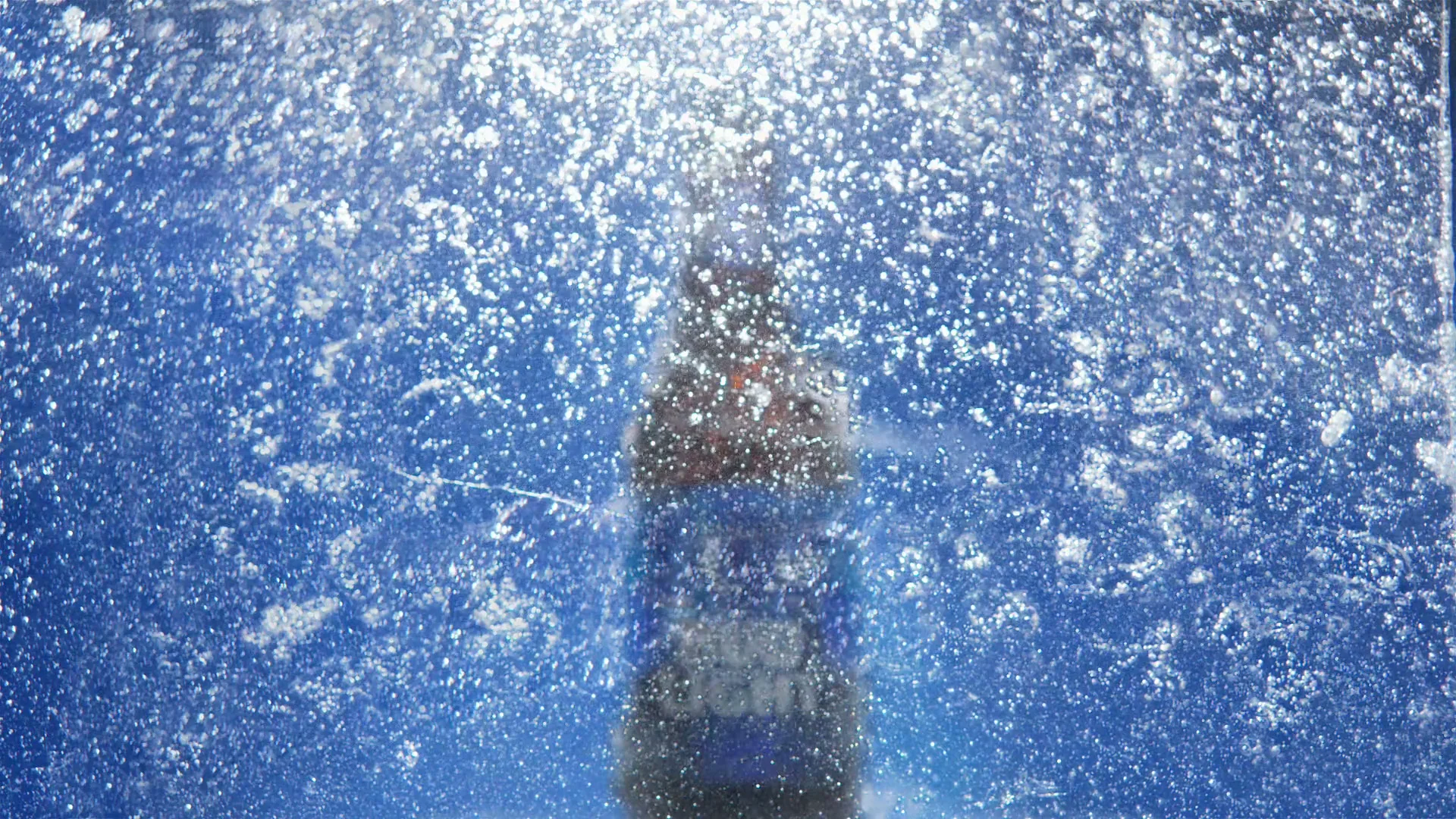 A Bud Light bottle is seen through a sheet of ice, with ice cracking and falling away to reveal the bottle and its label.