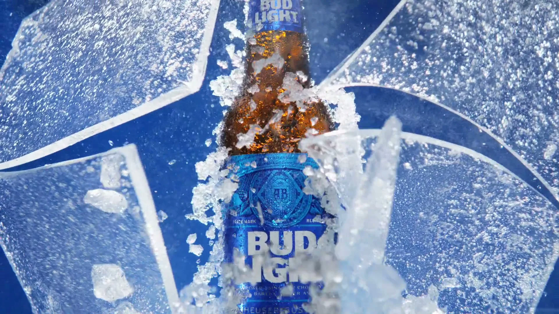 A Bud Light bottle, covered in ice, shatters the ice around it in slow motion against a blue background.