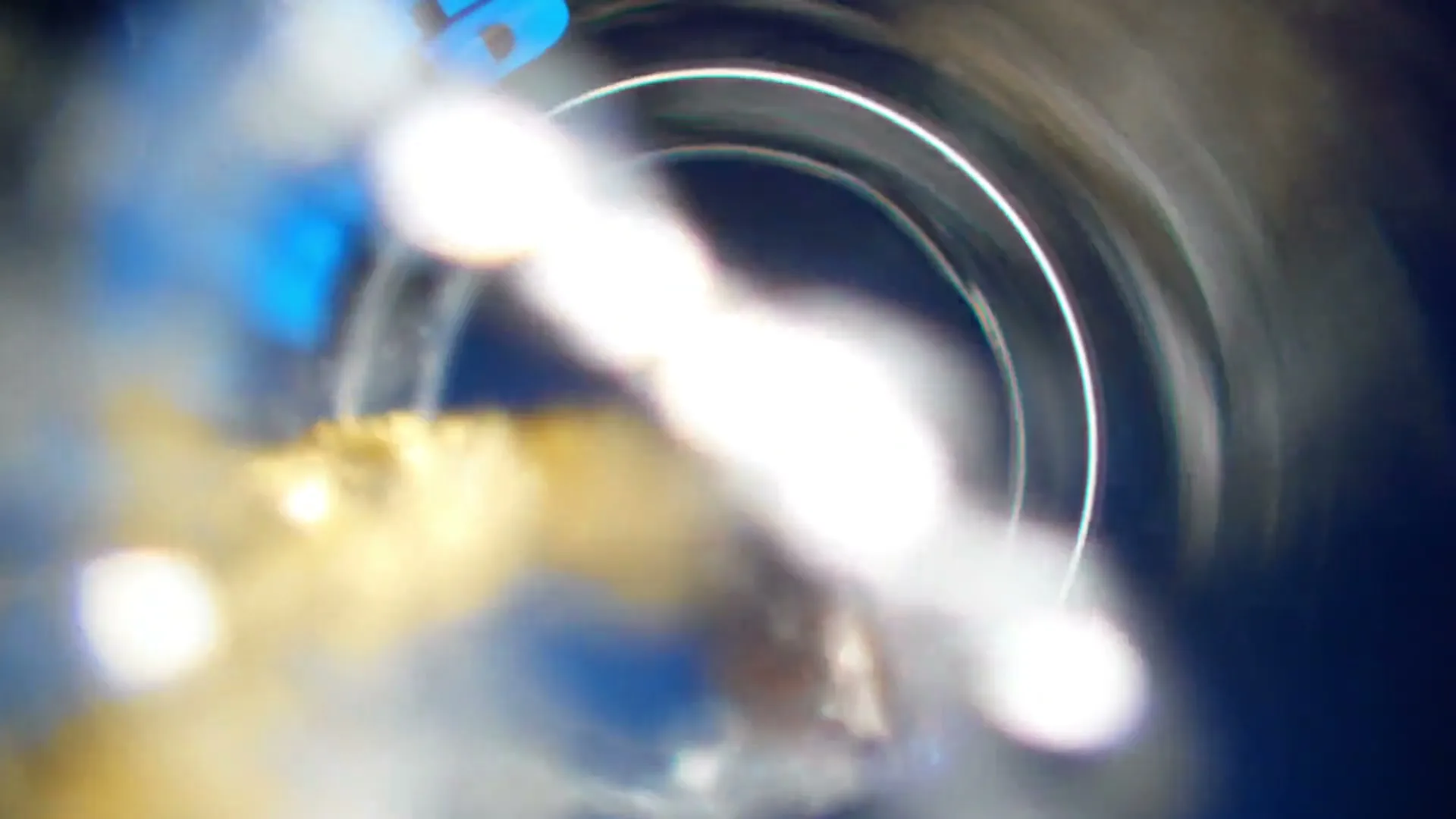 A macro shot of a Bud Light bottle opening, with beer and bubbles spilling out against a dark blue background.