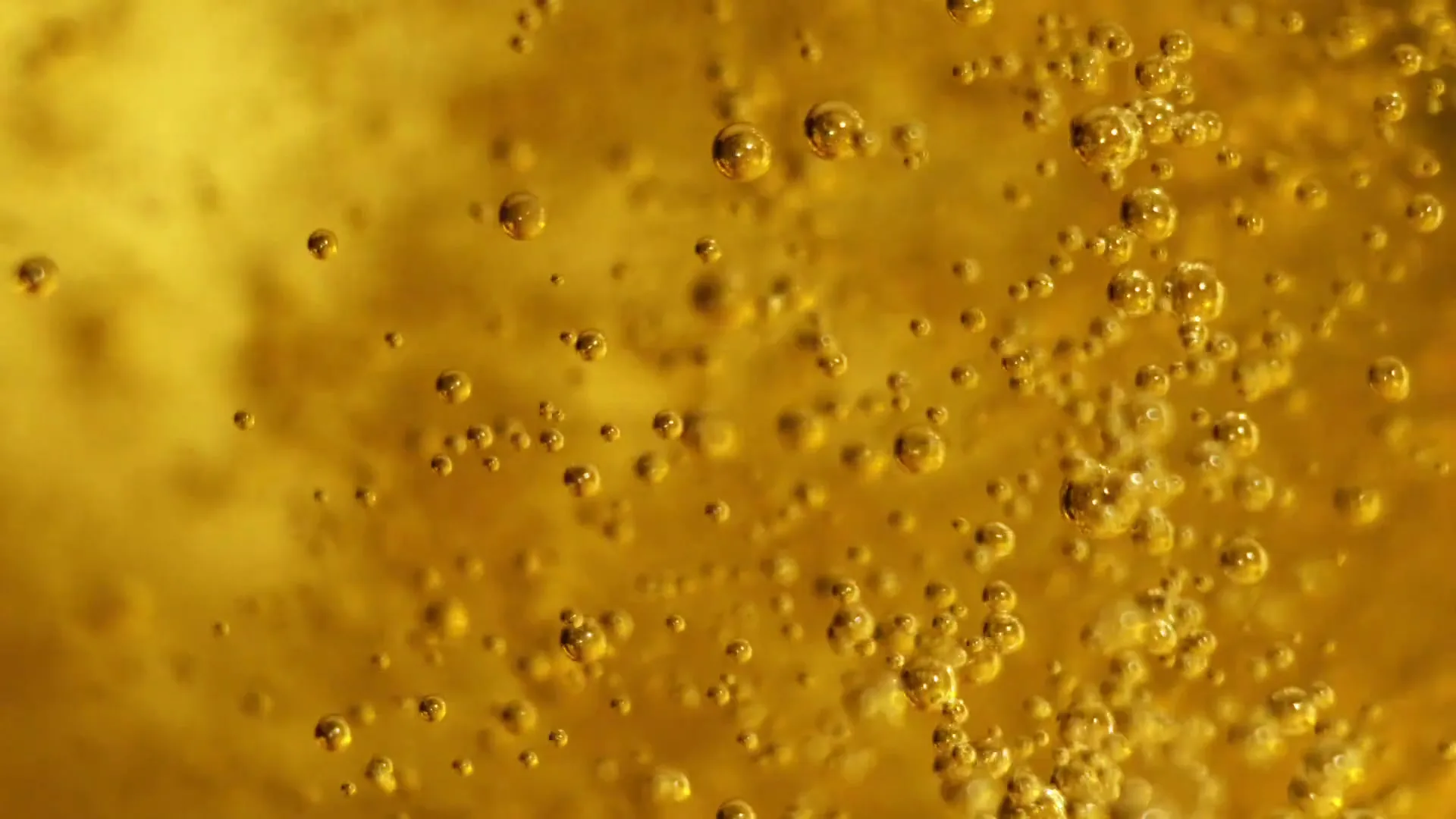 A macro shot of golden liquid with many small bubbles rising, creating a dynamic and effervescent visual.