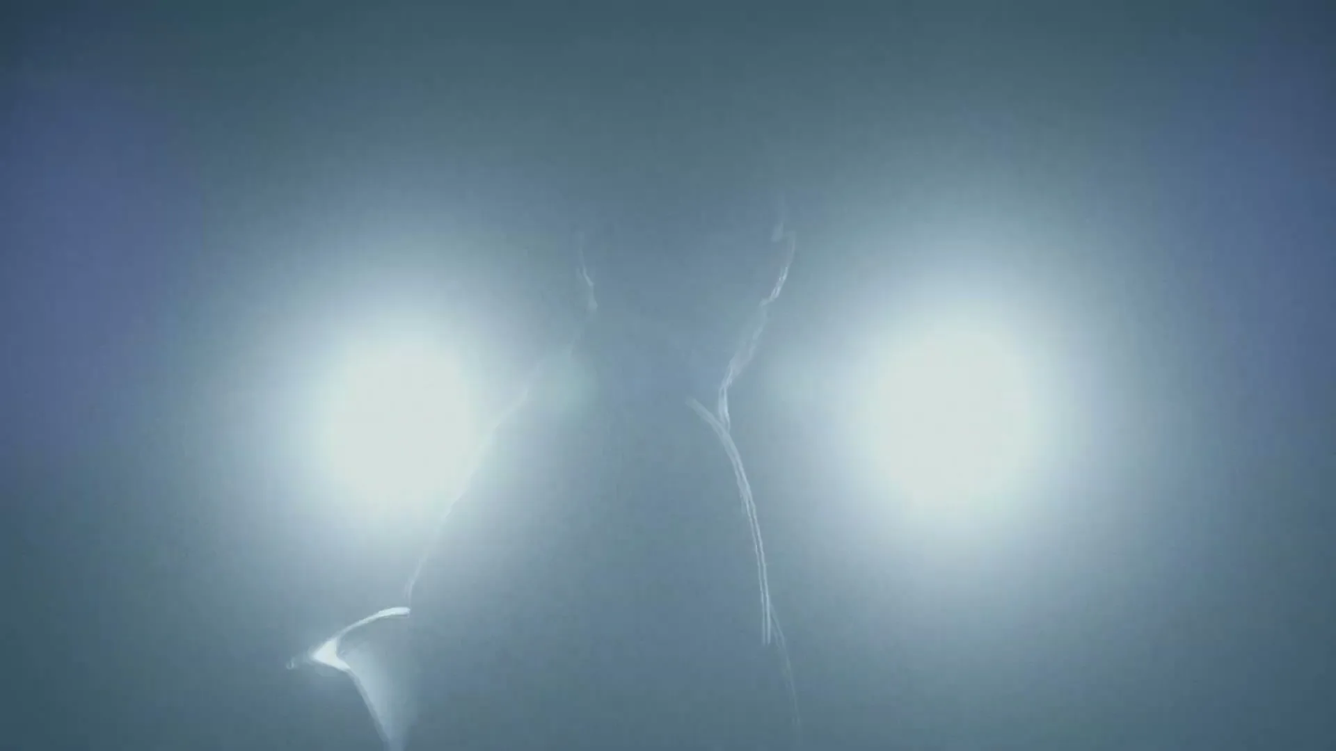A person's silhouette is visible against two bright, circular lights, creating a mysterious and high-contrast scene.
