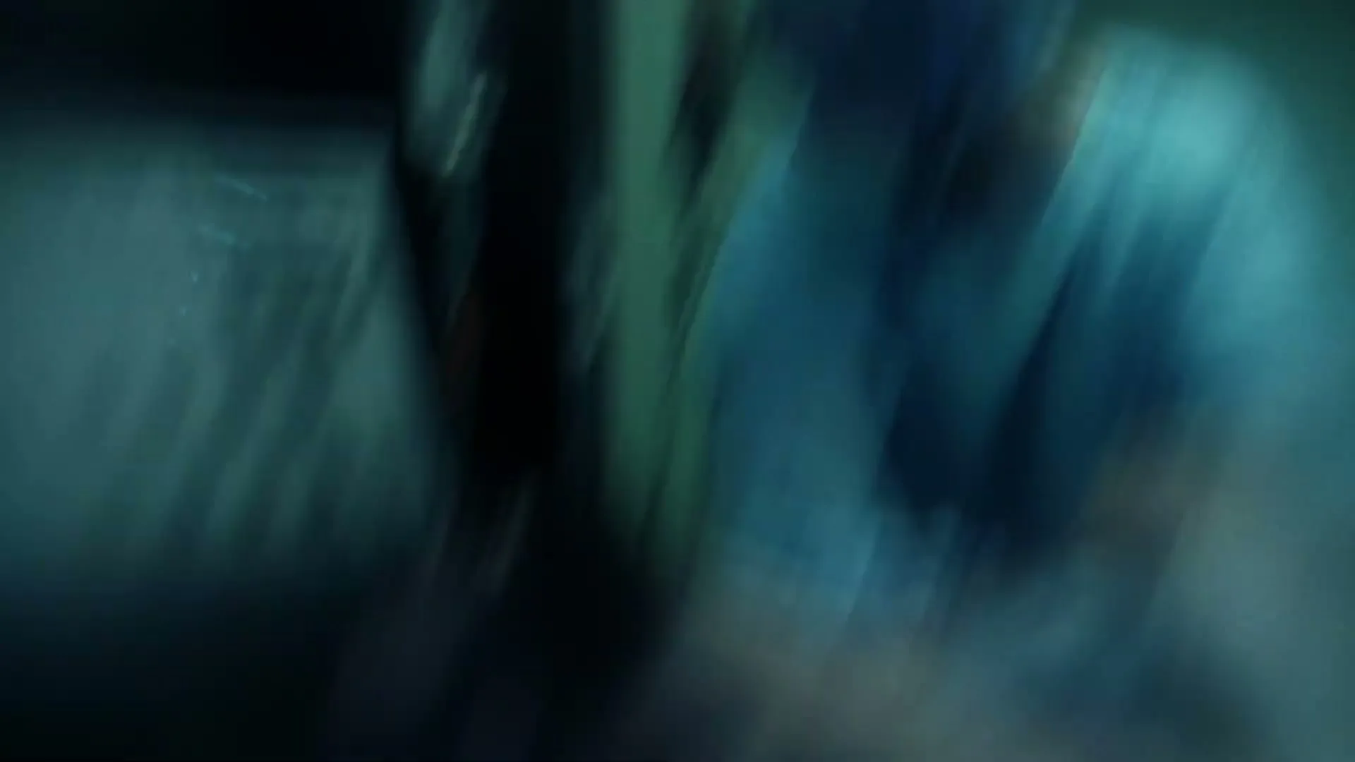A blurry shot of a patient lying on a hospital bed, with a surgeon in scrubs and a mask visible in the background, in a dimly lit operating room.