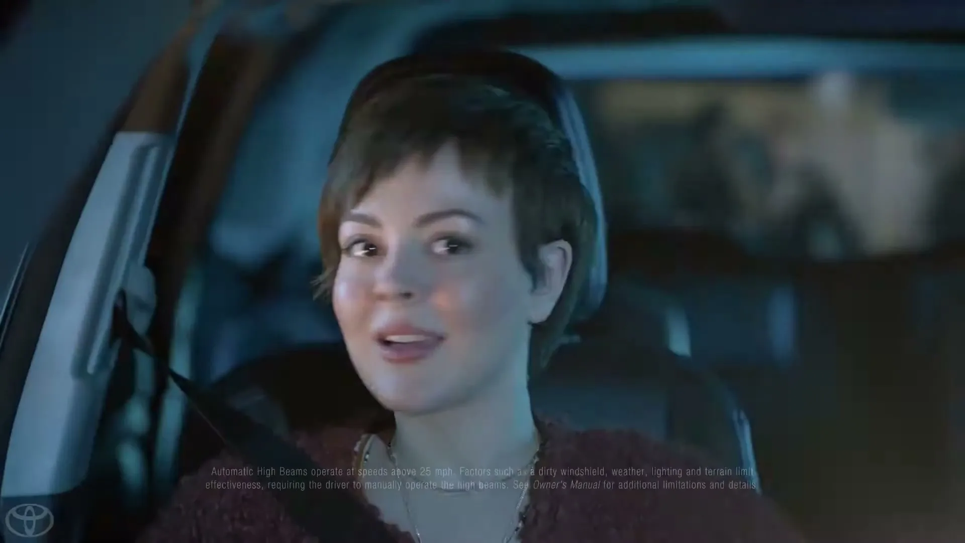 A young woman with short brown hair, wearing a dark top, looks forward with a surprised expression while sitting in the passenger seat of a car at night.