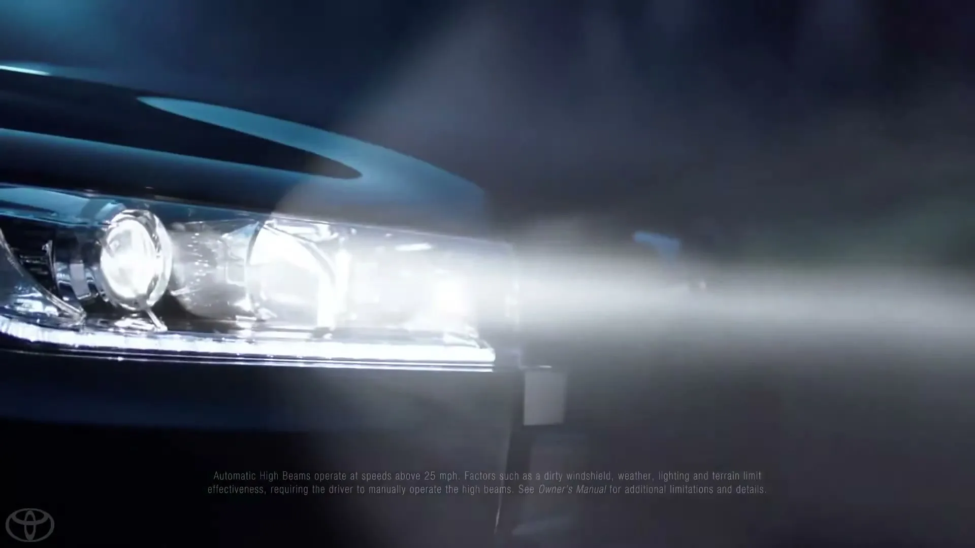 A close-up of a car's headlight, shining brightly into the dark, with a legal disclaimer and brand logo visible at the bottom.