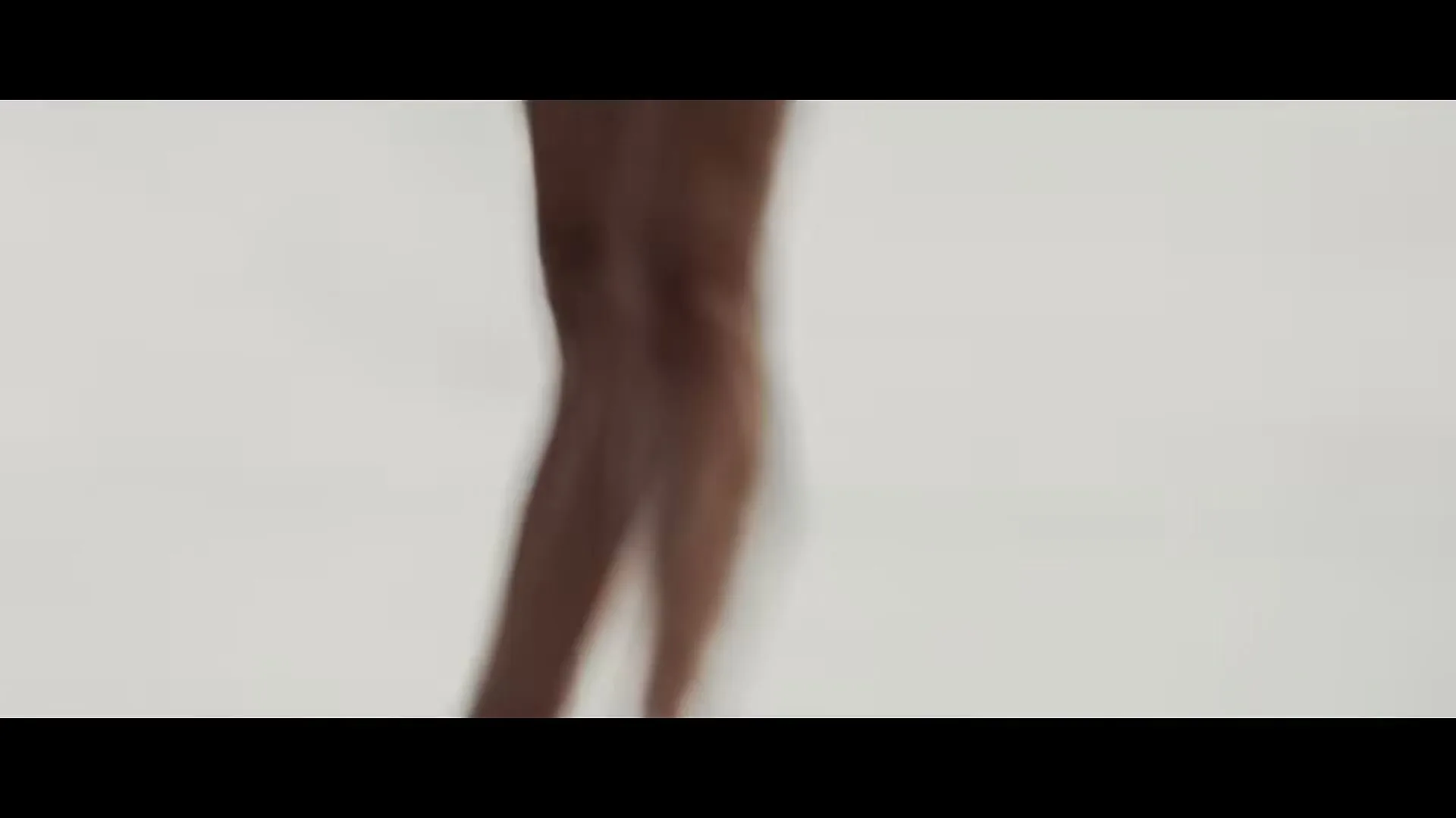 A blurry shot of a female ballet dancer's legs and feet in pointe shoes, standing on a light-colored floor.
