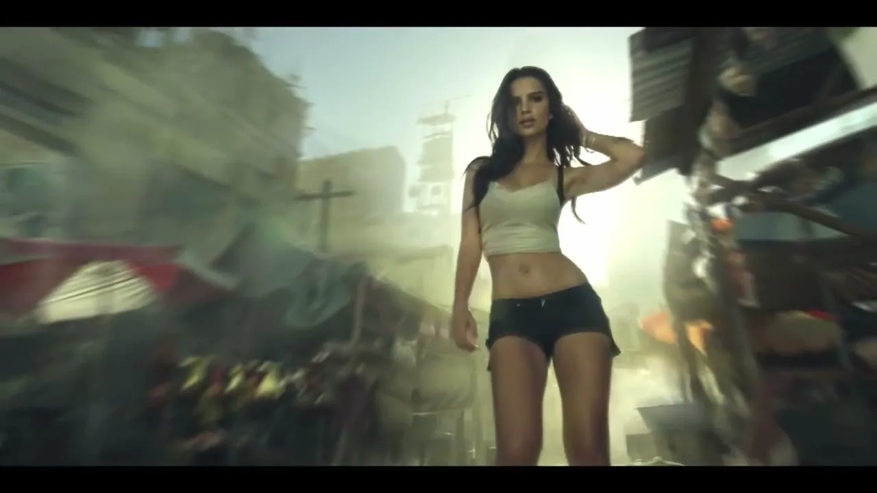 A young woman with long dark hair, wearing a tank top and shorts, stands confidently in a destroyed urban street.