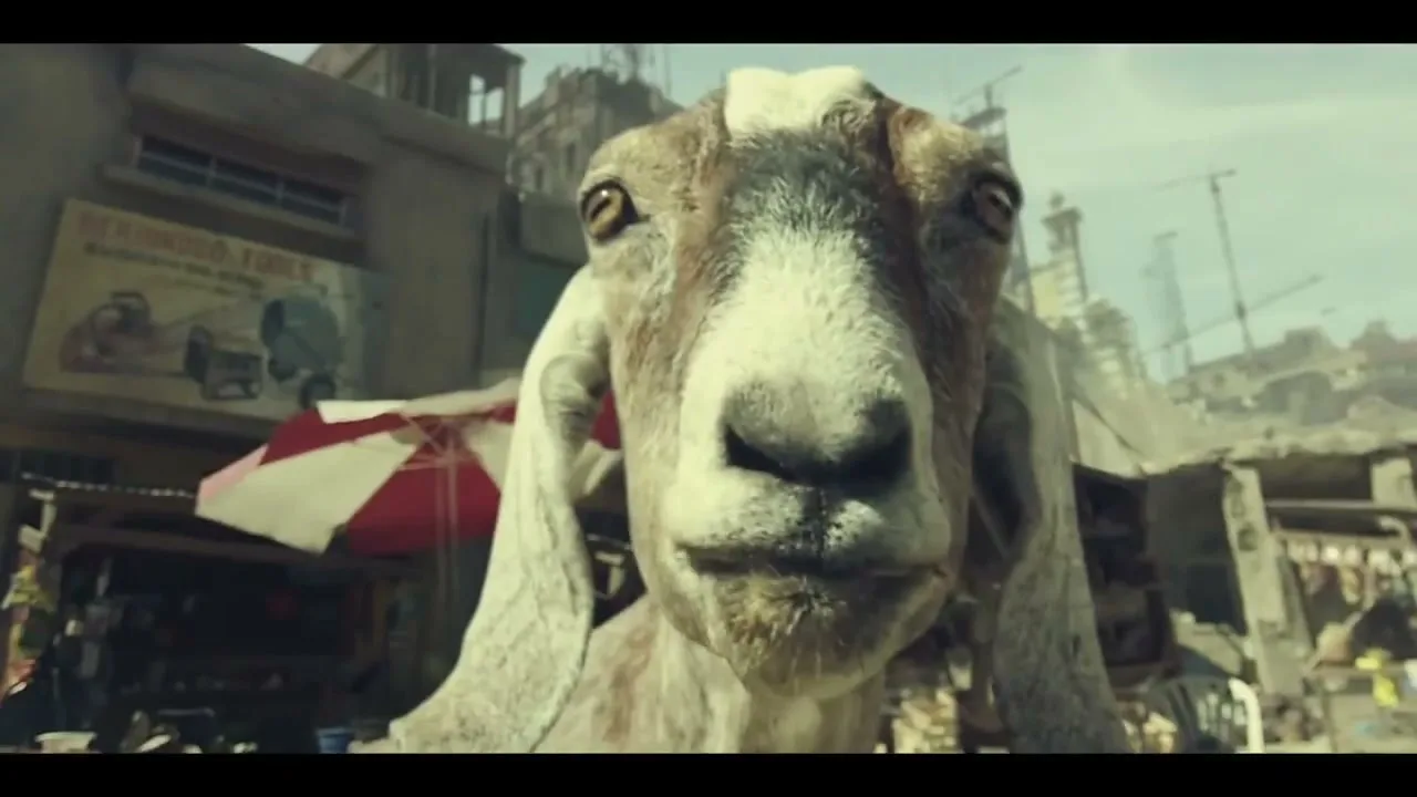 A woman with long dark hair looks at the camera, then a man in military gear with a rifle looks around a war-torn street, followed by a goat licking its nose, and then the man again as explosions happen around him.