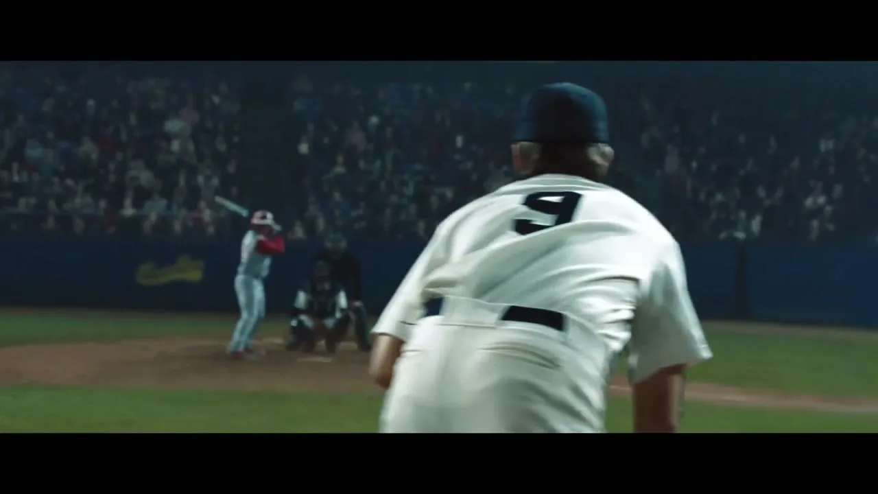 A baseball pitcher in a white uniform with the number 9 on his back throws a pitch from the mound in a stadium at night.