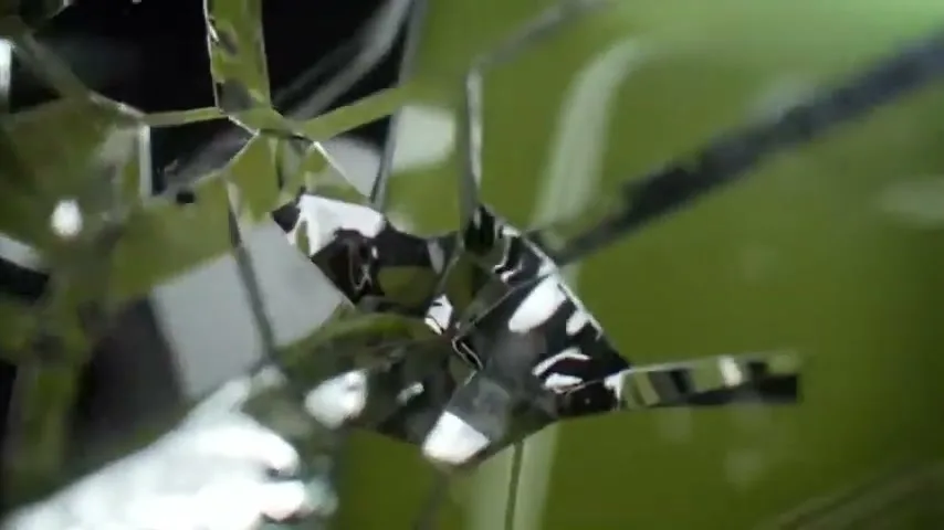 A close-up shot of a reflective, shattered surface with a green background, creating a dynamic and abstract visual.