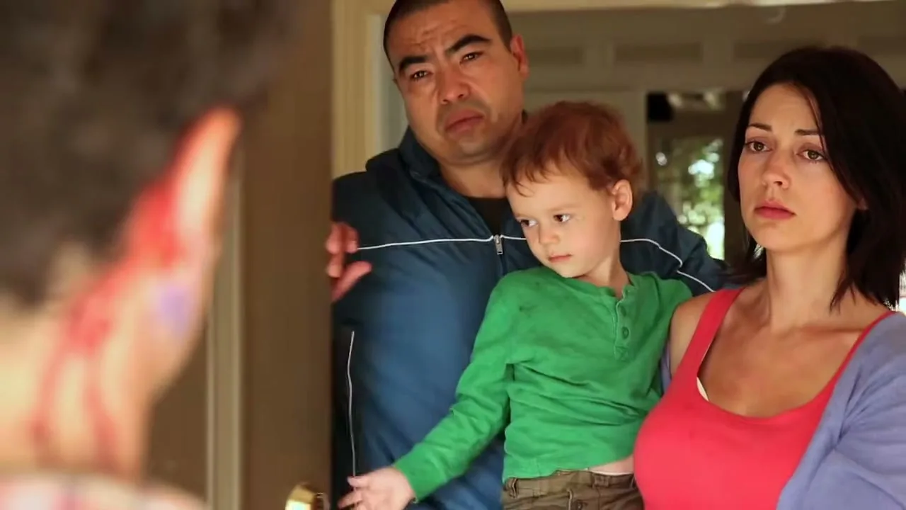 A woman holds a child while a man stands behind them, looking concerned as they open a door to an unseen person.
