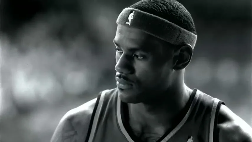 LeBron James, a male basketball player, looks up and to the right in a black and white shot on a basketball court.