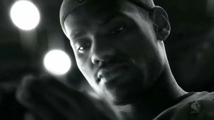 LeBron James, a male basketball player, looks directly at the camera while holding a basketball in a dark arena.