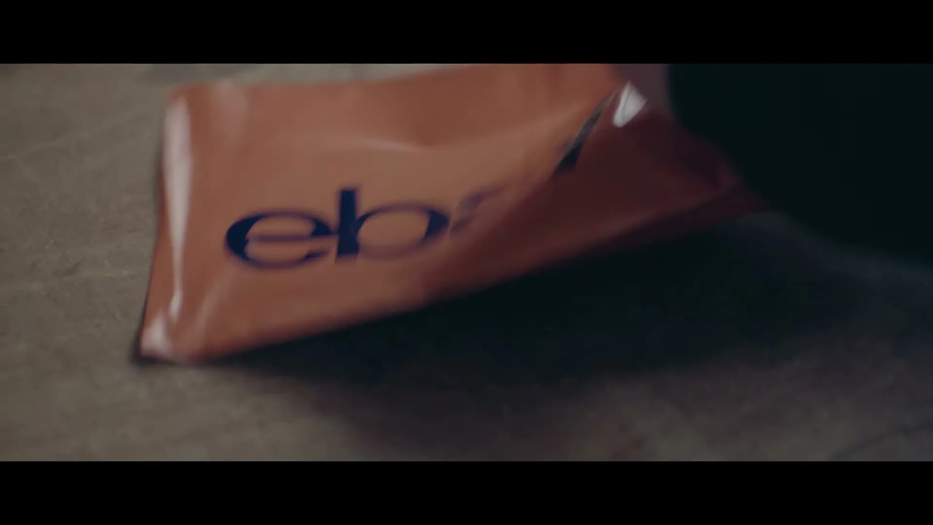 A person's hands are seen opening an orange eBay package on a textured surface, revealing the contents inside.