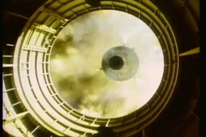 A rocket engine ignites, emitting smoke and fire, viewed from directly above within the launch tube.