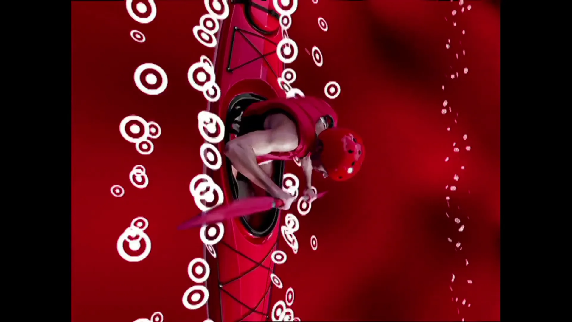 A male kayaker in a red kayak paddles through a red virtual space filled with white Target bullseye logos, as if falling.