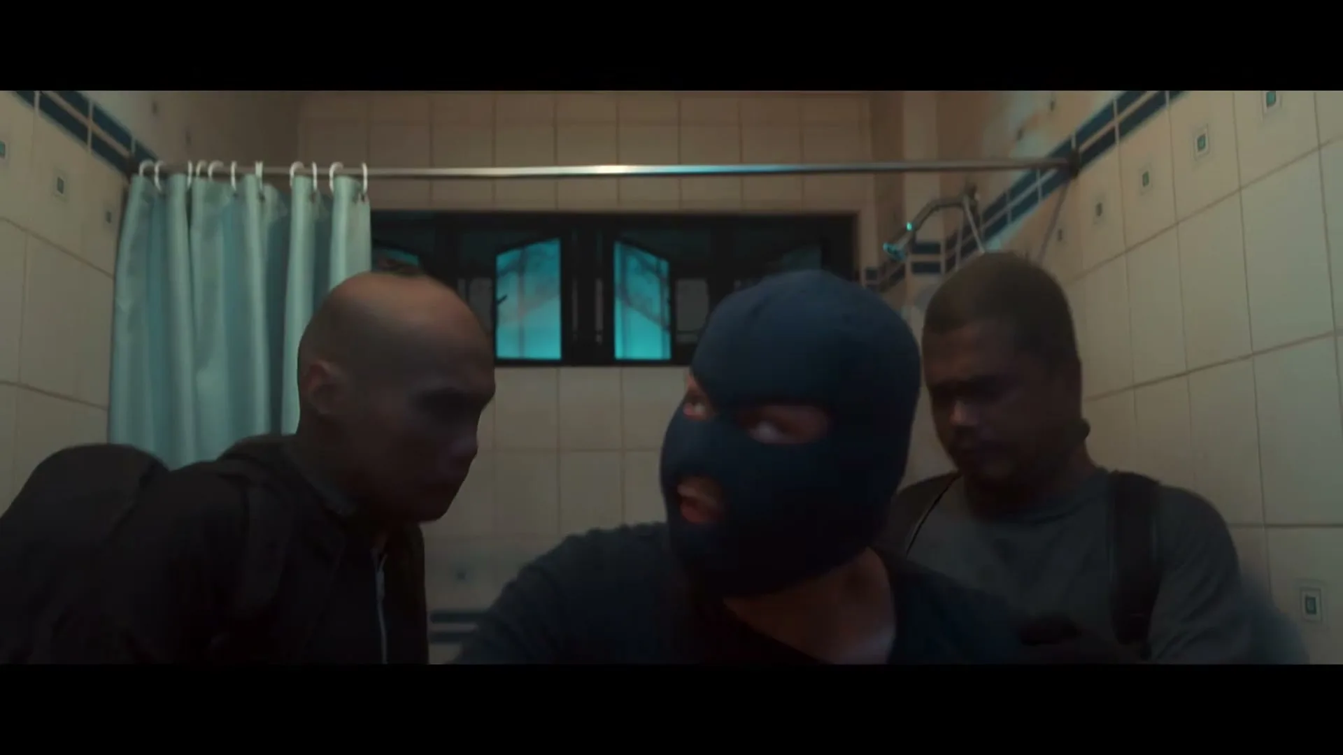 Three male burglars, one wearing a balaclava, are in a tiled bathroom, with the masked man reaching up to remove a light bulb.