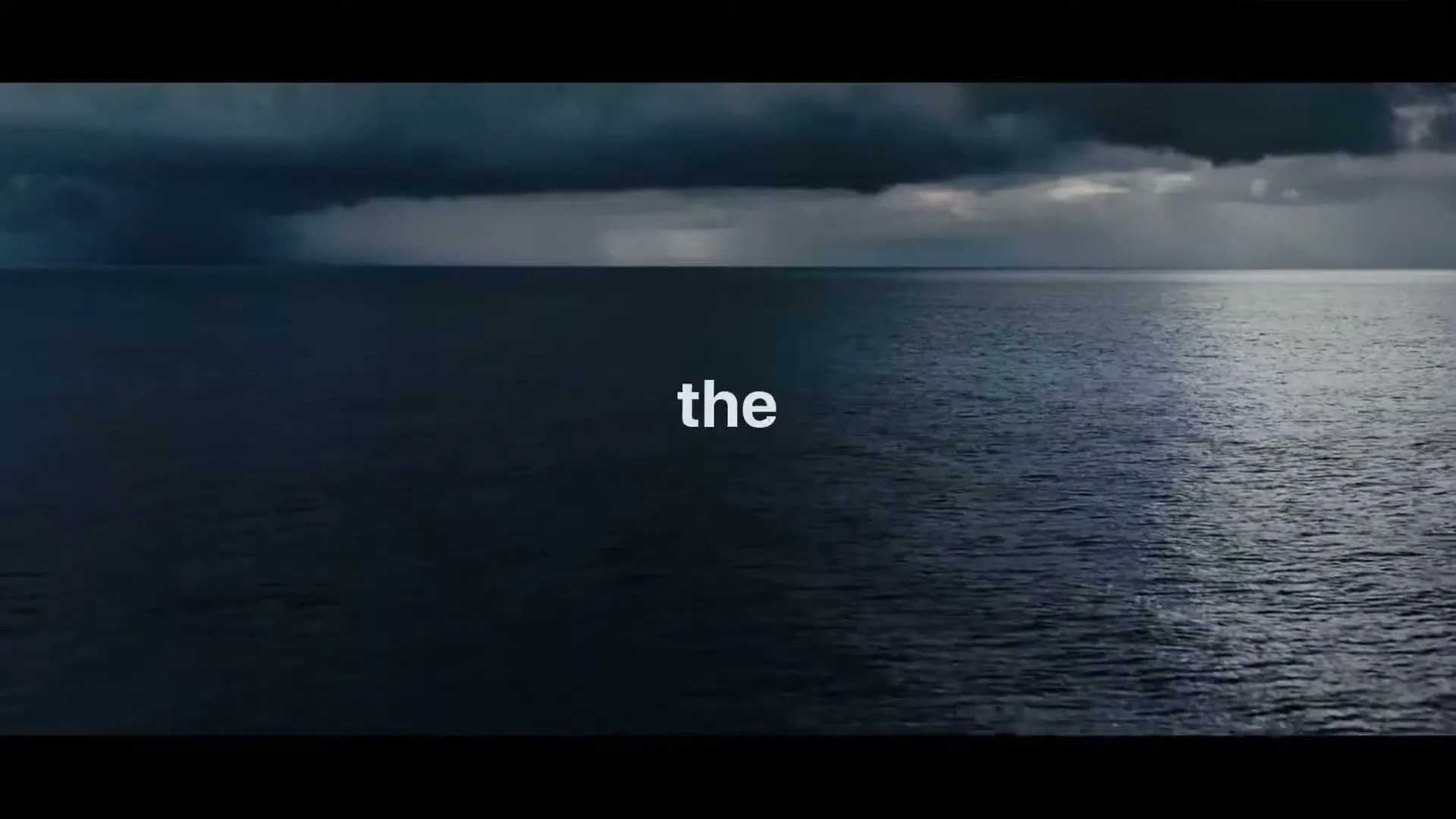 A wide shot of a dark, stormy ocean under a dramatic sky, with text appearing on screen.