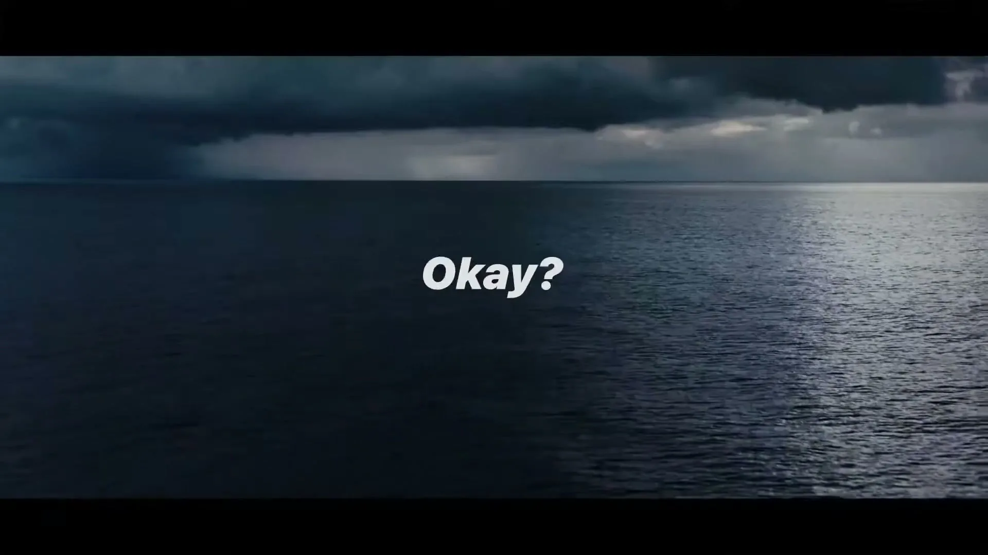 On-screen text appears over a wide shot of a dark ocean under a stormy sky, with a faint line of light on the horizon.