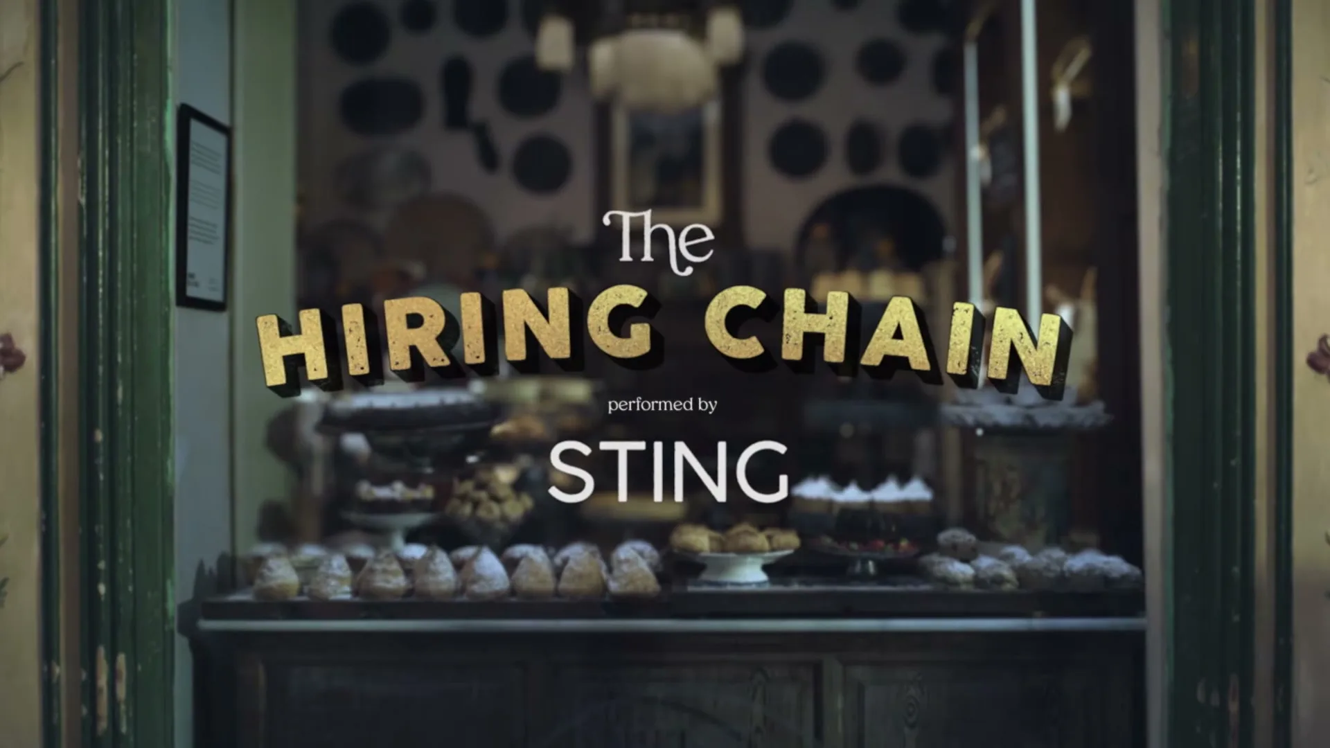 The title card for "The Hiring Chain" performed by Sting is displayed over a blurred background of a bakery window filled with pastries.