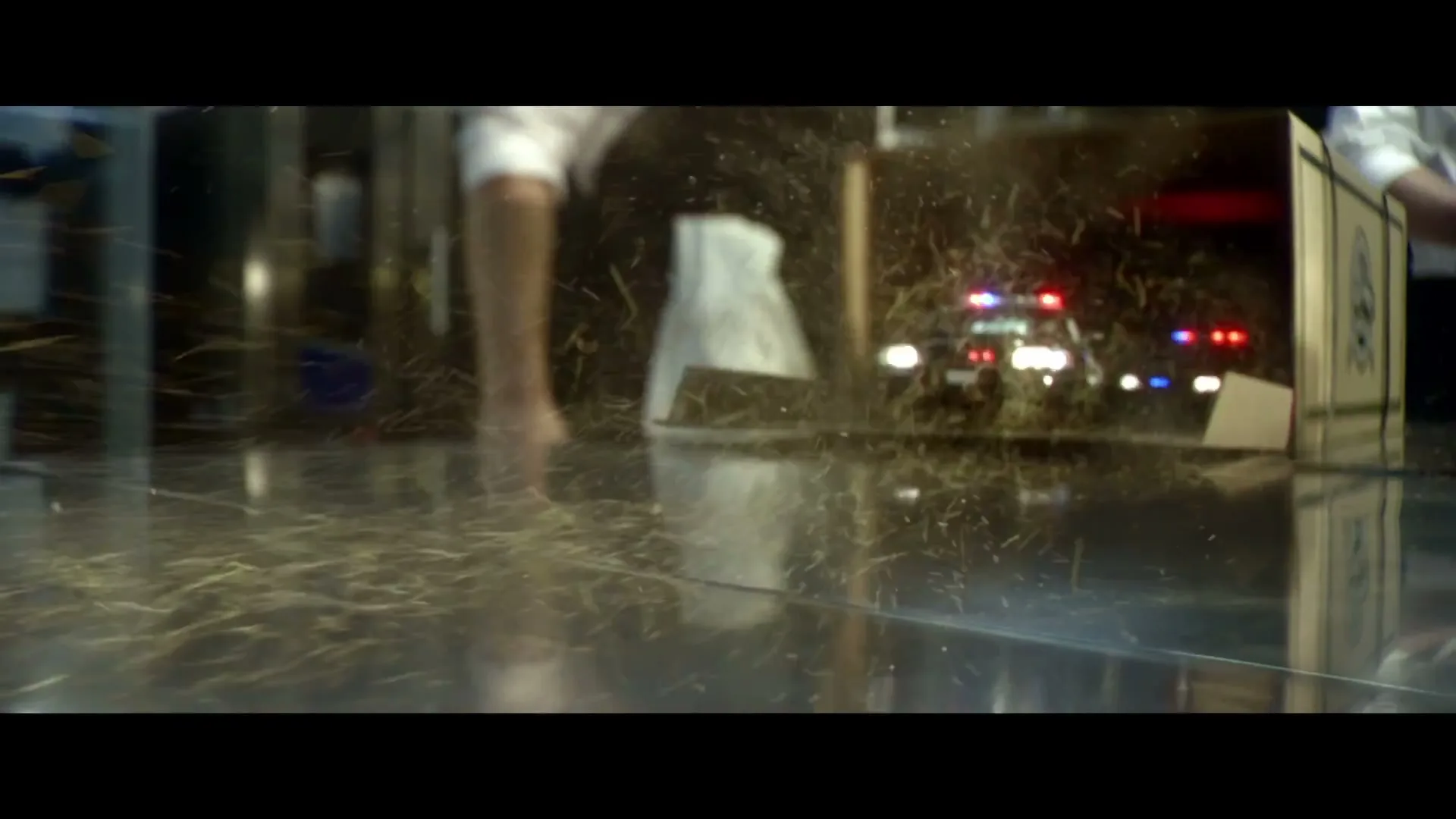 A chef in a professional kitchen opens a box, revealing a miniature car chase with police cars and masked figures in a car.