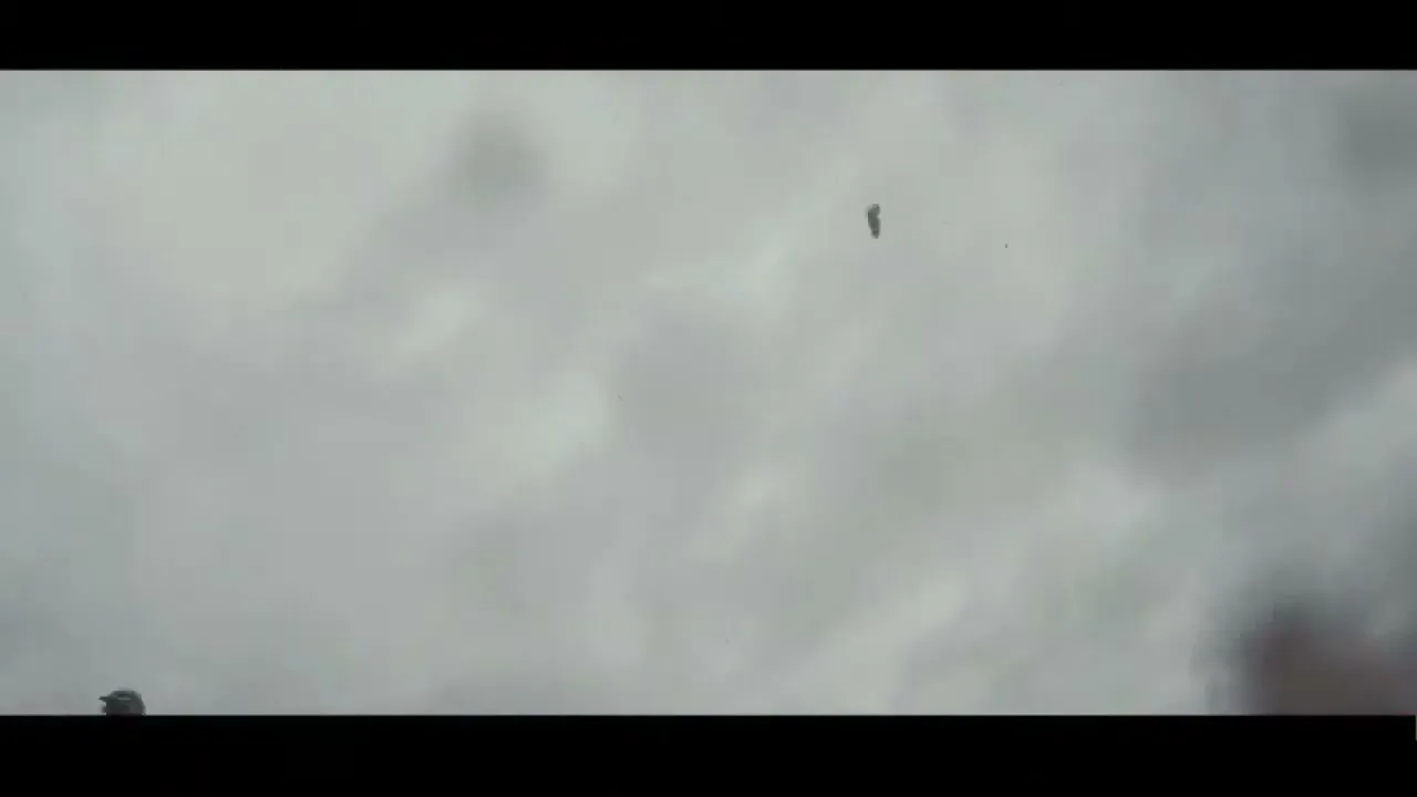 A dirt biker in full gear jumps high into the air against a cloudy sky, then falls out of frame.