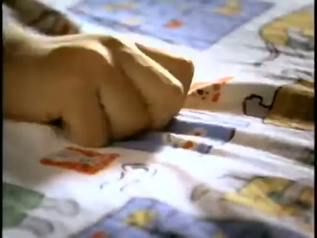 A child's hand quickly snatches a small stack of coins from a patterned bedsheet.