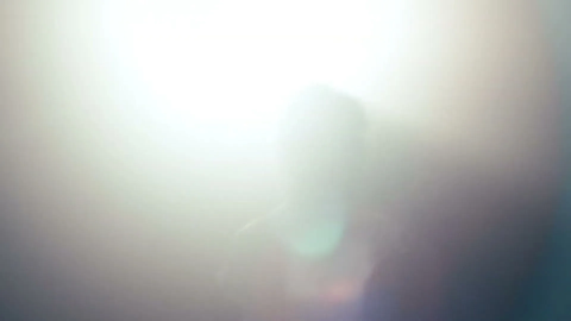 A person is silhouetted against a bright, hazy light source, with lens flare visible, creating a mysterious and ethereal atmosphere.