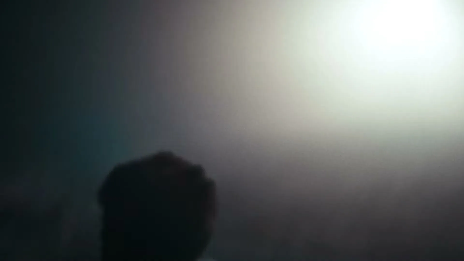 A young person with a dirty face and closed eyes is seen in a blurry, dark, and intense close-up shot.