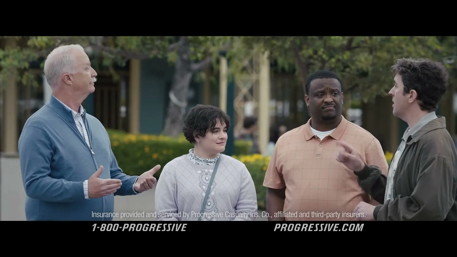 Dr. Rick, a middle-aged man, talks to a small group of people outdoors, gesturing with his hands as they listen intently.