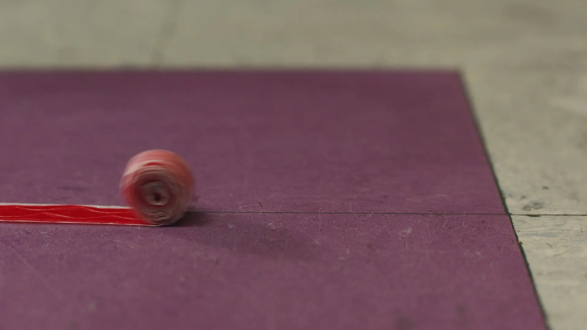A red Fruit by the Foot unrolls itself across a purple surface, revealing its long, flat form.