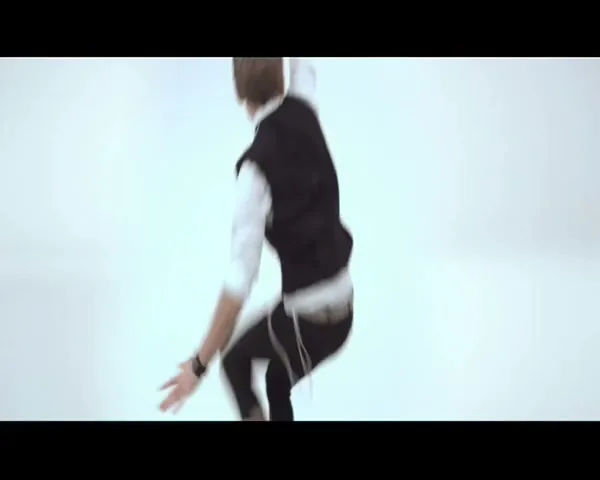 A man in a white shirt and black vest appears suddenly, shouts, then shrinks and runs away in a white studio.