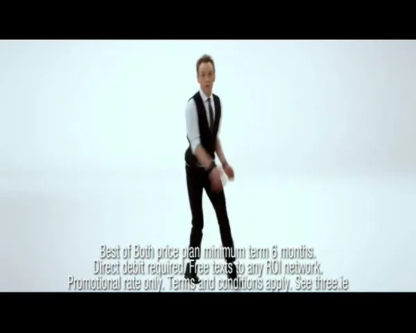 A man in a black vest and white shirt dances energetically, then stands still as confetti falls around him in a white studio.