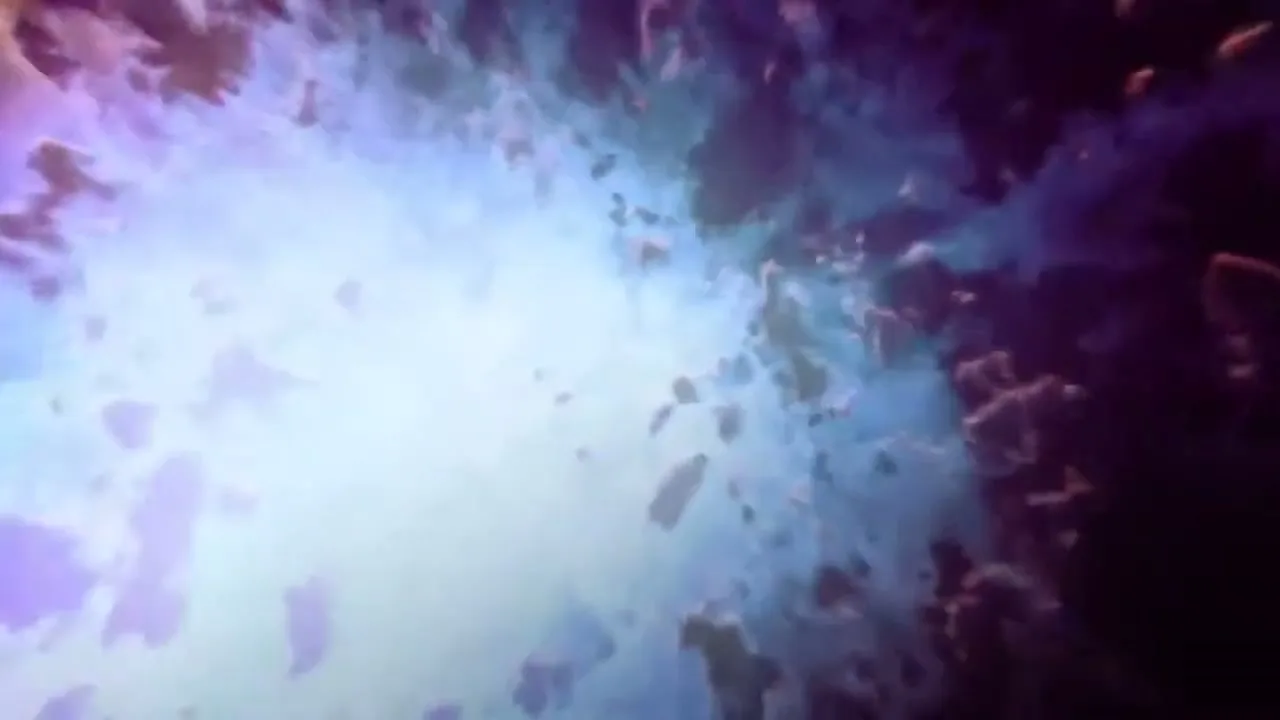 A camera zooms into a car's headlight, revealing a vibrant, abstract, purple and blue nebula with floating debris, symbolizing the car's inner workings.