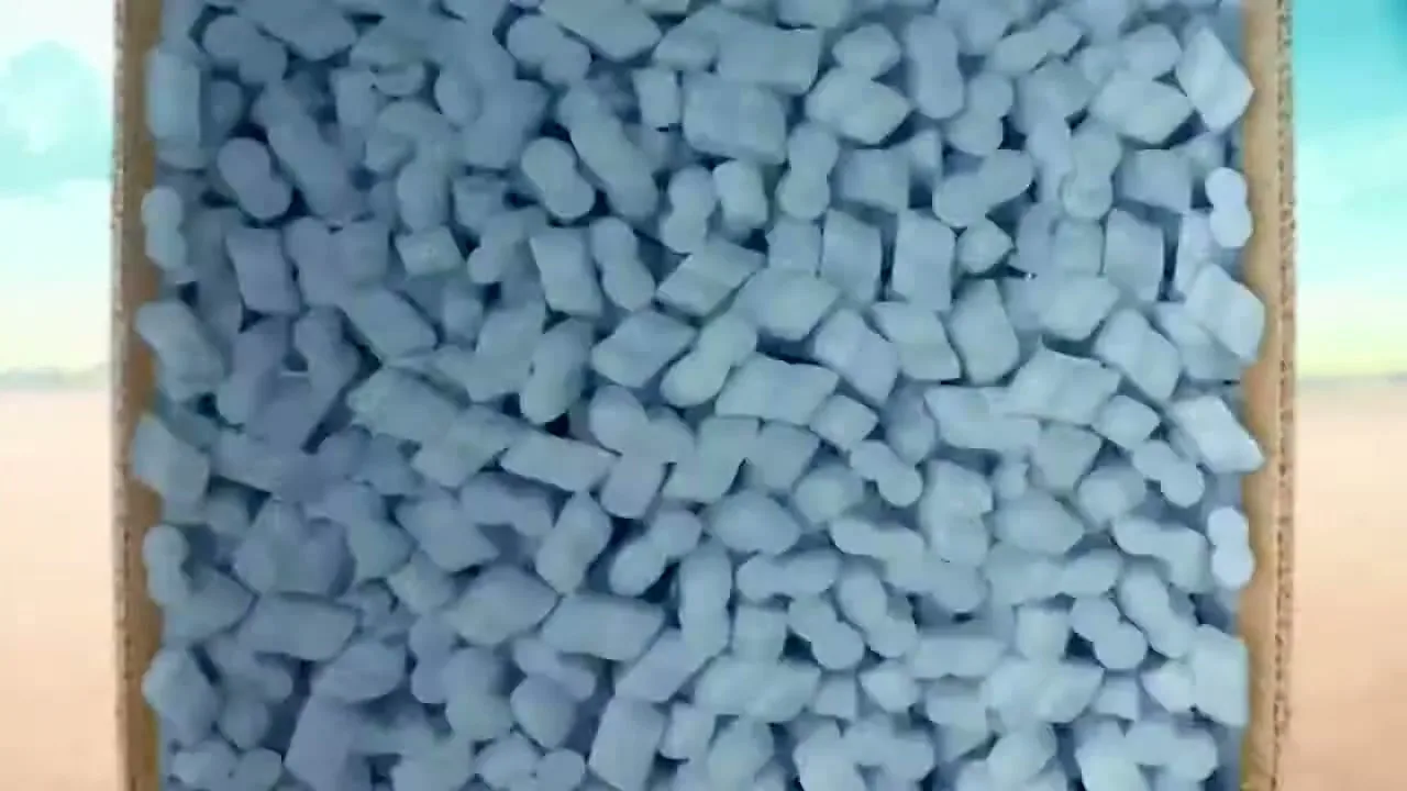A cardboard box filled with white packing peanuts is seen from above, with a desert landscape in the background under a blue sky.