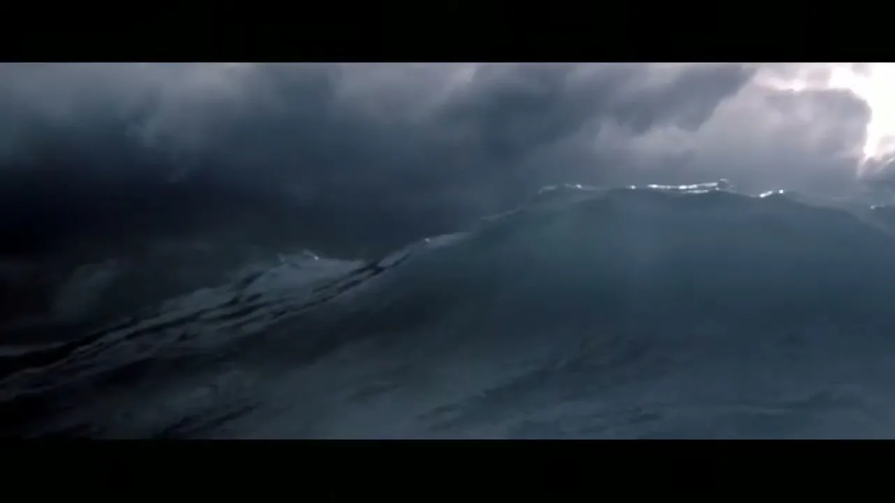 A massive, dark wave with white foam crests under a stormy, dark sky with a sliver of bright light.
