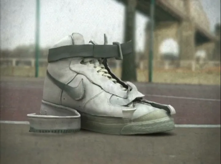 A white high-top sneaker on a basketball court transforms, with parts of the shoe peeling away and reforming into a newer design.