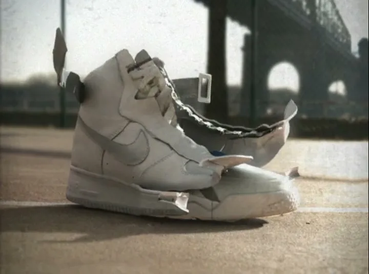 A white Nike sneaker transforms into a newer model on a tennis court, with the Eiffel Tower visible in the background.