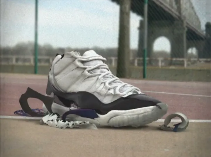 A white and black basketball shoe rapidly assembles itself from torn pieces on a tennis court, with a bridge in the blurry background.
