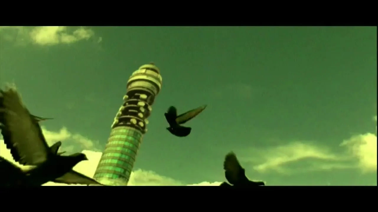 Pigeons fly past the BT Tower in London, England, against a green-tinted sky with white clouds.