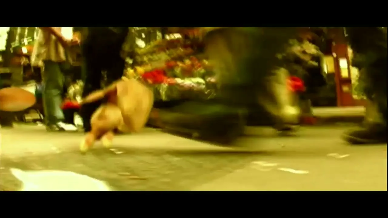 A low-angle shot shows a raw chicken being dribbled like a basketball on a busy city street, with blurred pedestrians and shops in the background.