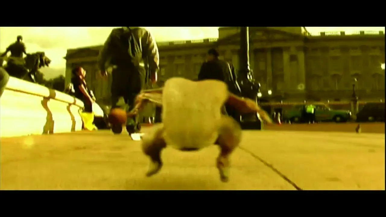 A raw chicken with human legs and arms runs on a city street in front of a large building, with people walking in the background.