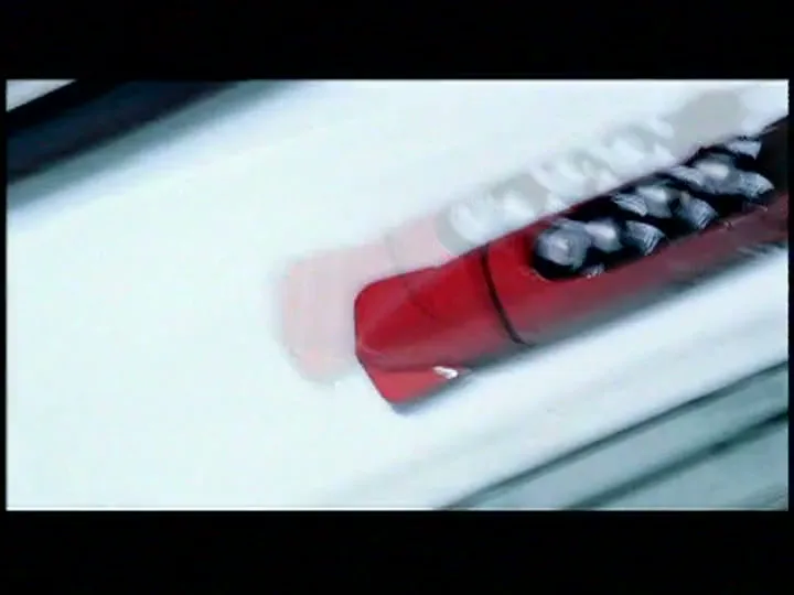 A red bobsled with a team of four athletes speeds down an icy track, captured in a dynamic, motion-blurred shot.